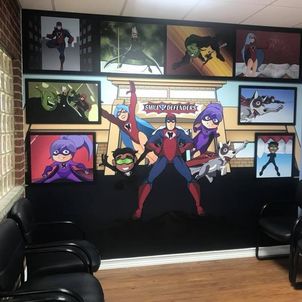 Picture of a dental office waiting room with a Smile Defender mural on the wall.